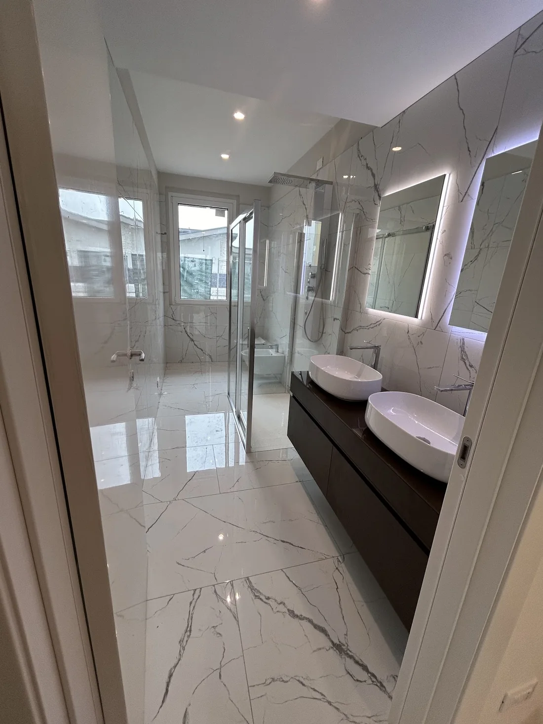 Bagno con rivestimento effetto marmo e doppio lavabo