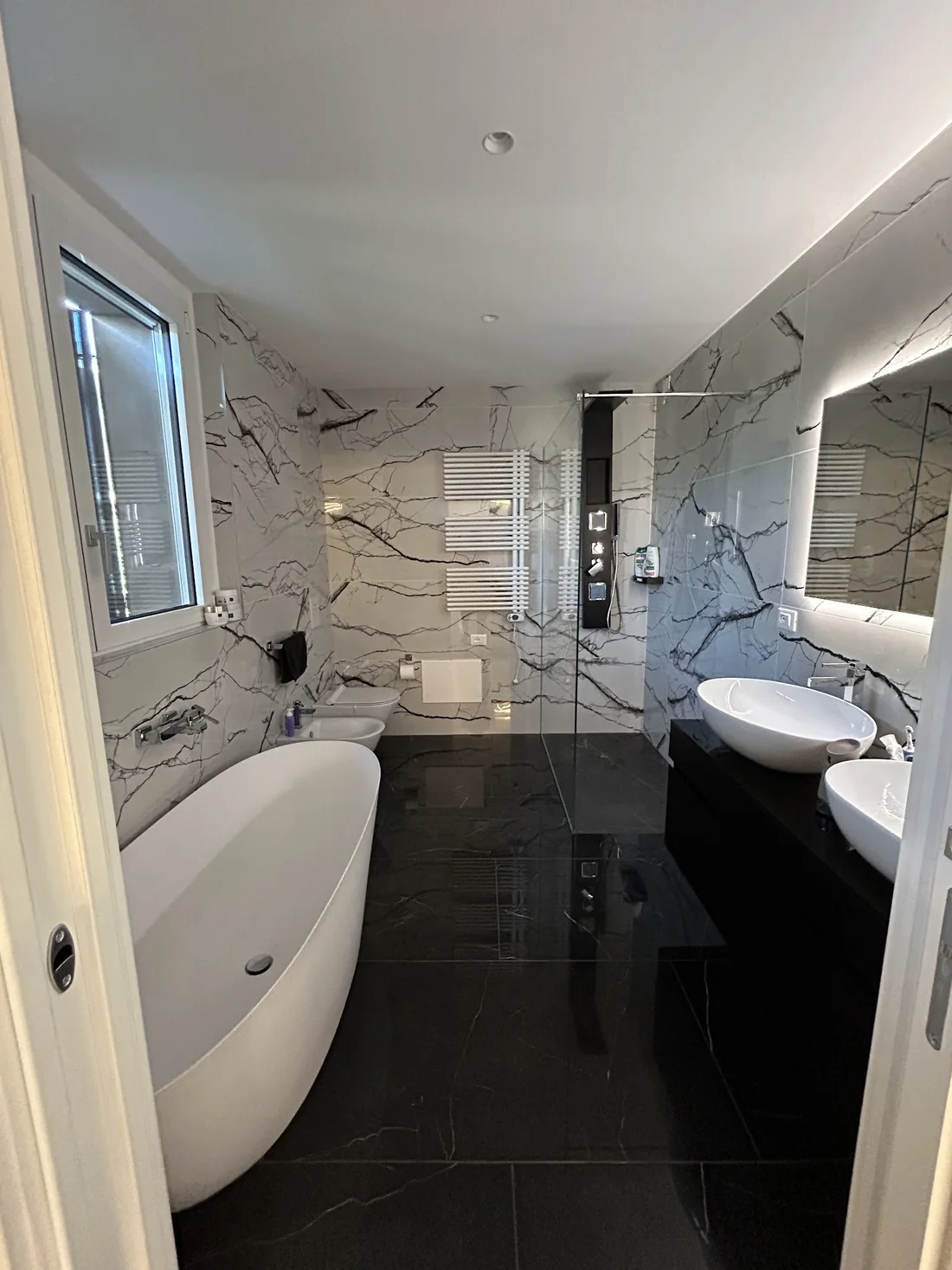 Bagno con vasca, doppio lavabo e illuminazione a specchio